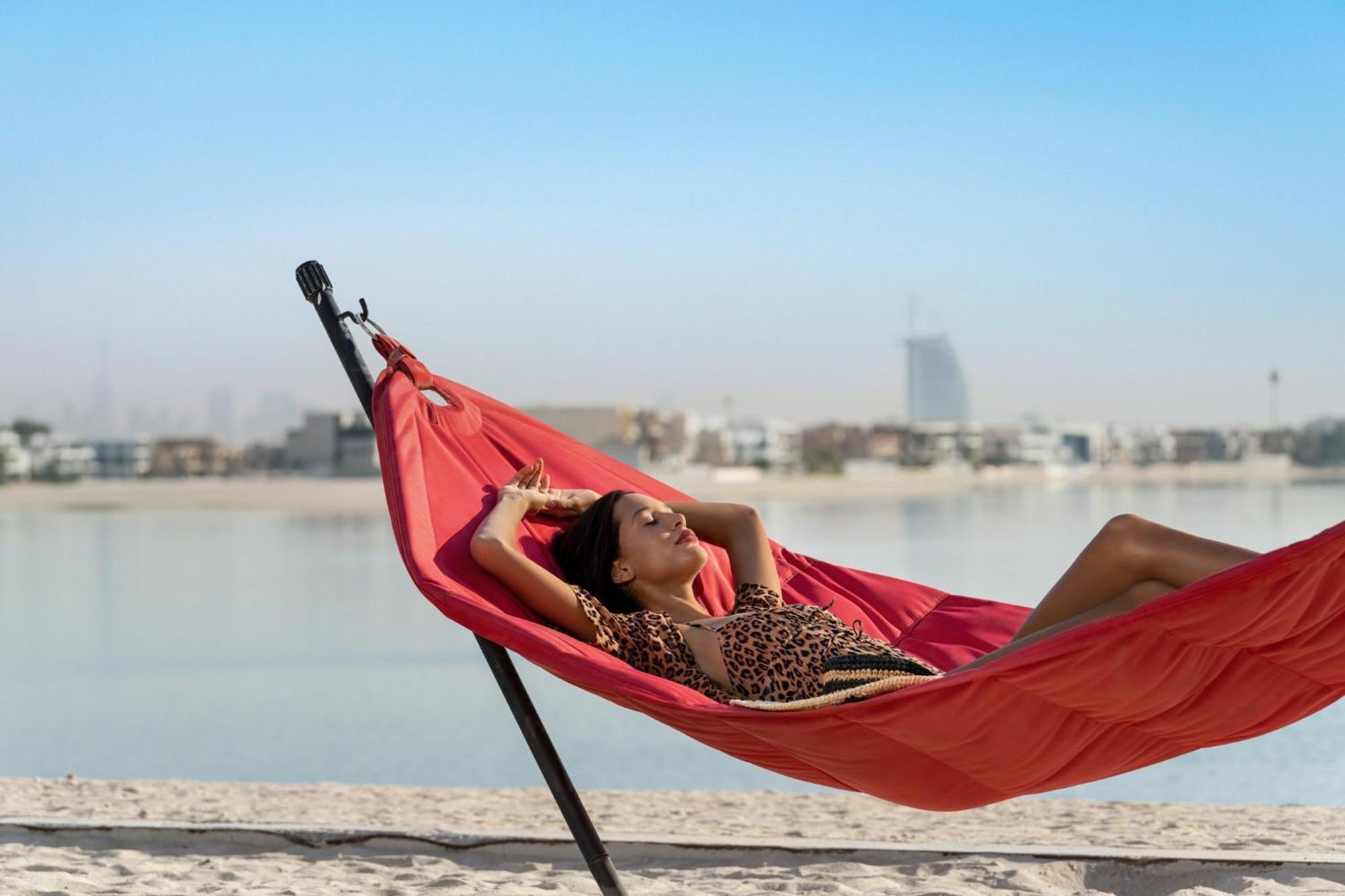 Th8 Palm Dubai Beach Resort, Vignette Collection By Ihg Екстериор снимка A woman relaxing in a hammock